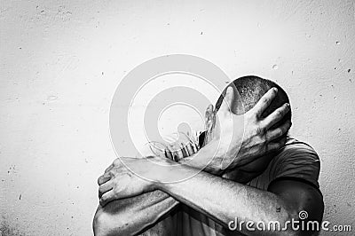 Homeless man drug and alcohol addict sitting alone and depressed on the street feeling anxious and lonely, social documentary conc Stock Photo