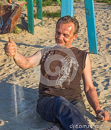 Homeless Man. Poor people in the children`s Playground at sunse Stock Photo