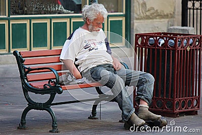 Homeless Man Sitting on a Park Bench on Stephen Avenue in Calgary Alberta Editorial Stock Photo