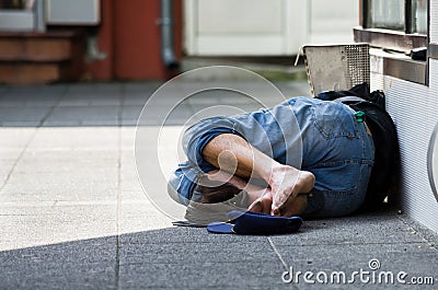 Homeless man sleeps on the street, in the shadow Stock Photo