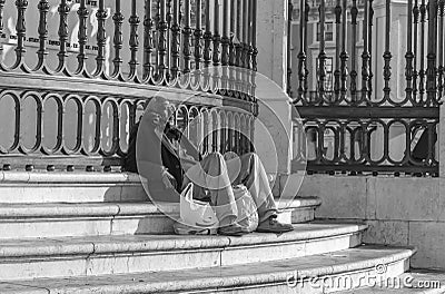 Homeless man on the steps of the monument of king jose I. Editorial Stock Photo