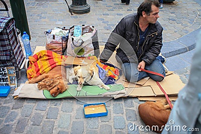 Homeless man with two dogs asks alms from passers-by sitting on the ground Editorial Stock Photo