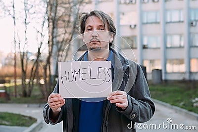 A homeless person holds a sign , asks for work, and seeks help. The concept of poverty and homelessness Stock Photo