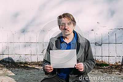 A homeless person holds a sign , asks for work, and seeks help. The concept of poverty and homelessness Stock Photo