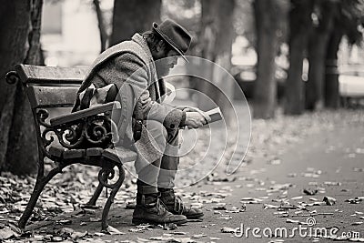 A homeless reading on a bench Editorial Stock Photo