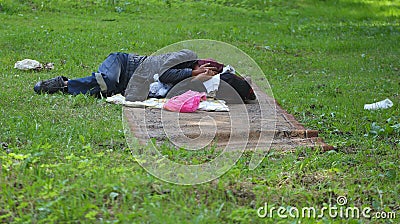 A homeless tramp sleeps on a dirty carpet spread on the grass Editorial Stock Photo
