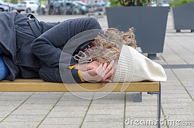 Homeless woman sleeping rough on a bench Stock Photo