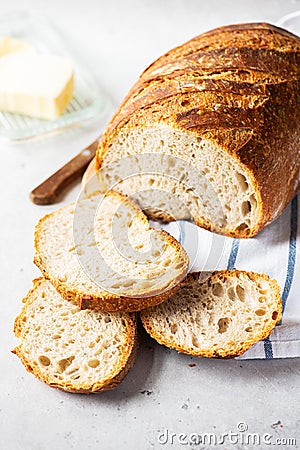 Homemade artisanal sliced sourdough bread on a napkin and butter with knife. Healthy home baking concept Stock Photo