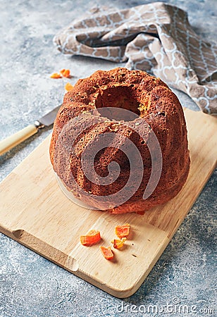 Homemade autumn carrot cake with candied fruits on wooden cutting board Stock Photo