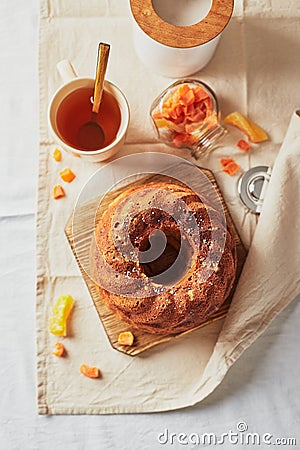 Homemade autumn carrot cake with candied fruits on wooden cutting board and cup of tea Stock Photo