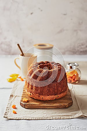 Homemade autumn carrot cake with candied fruits on wooden cutting board and cup of tea Stock Photo