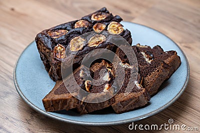 Homemade banana bread cut into slices on a blue plate. Cutted banana on top Stock Photo