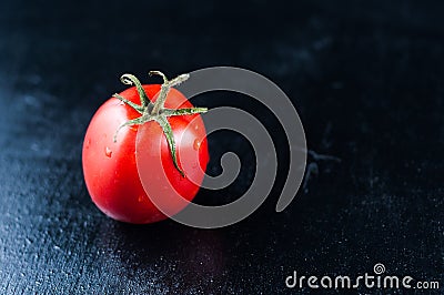 Homemade beautiful red tomato on a black wooden background in drops of water Stock Photo