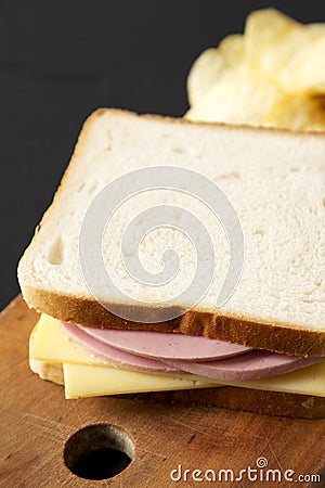 Homemade Bologna Cheese Sandwich with Chips on a rustic wooden board on a black background, side view Stock Photo