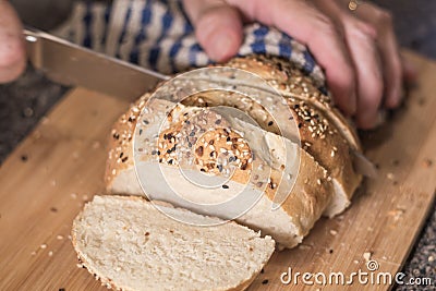 Homemade bread loaf with everything seasoning being sliced by hand Stock Photo