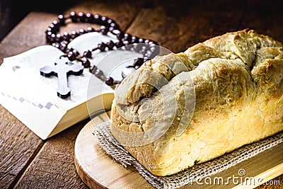 Homemade bread made in the Easter and Eucharist period, called Christ bread, religious symbol, with Bible and crucifix in the Stock Photo