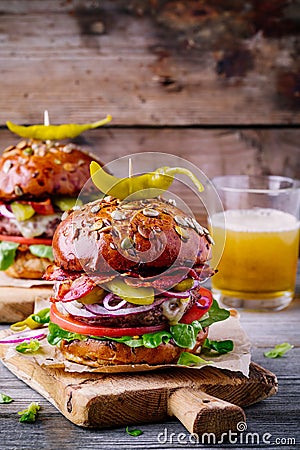 Homemade burgers with whole grain bun, fried bacon and spicy pickled peppers Stock Photo