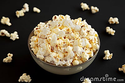 Homemade Buttered Popcorn with Salt in a Bowl on a black background, side view Stock Photo