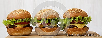 Homemade cheeseburgers on a bamboo board, side view. Closeup Stock Photo