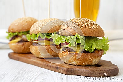 Homemade cheeseburgers on rustic wooden board and glass of cold beer, side view. Closeup. Selective focus Stock Photo