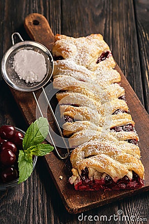 Homemade cherry puff pastry braid, on blue wooden background. Stock Photo