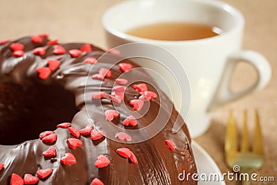 Homemade chocolate cake decorated with small caramel hearts and cup of tea Stock Photo