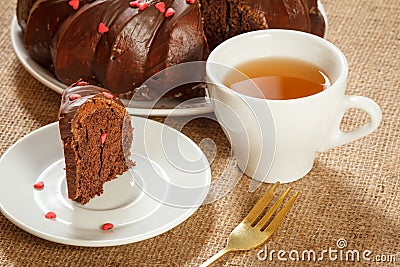 Homemade chocolate cake decorated with small caramel hearts and cup of tea Stock Photo