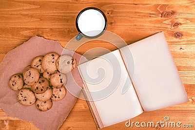 Homemade chocolate chip cookies, milk cup and open book Stock Photo