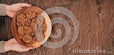 Homemade chocolate cookies on plate in male hands on wooden table. Stock Photo