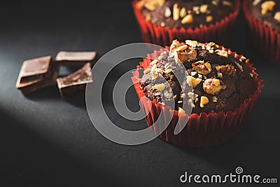 Homemade chocolate muffins or cupcakes sprinkled of nuts on dark background Stock Photo