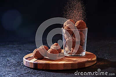 Homemade Chocolate Truffles in Glass with Sifting Cocoa on Wooden Board on Dark Stone Table and Background. Copy Space Stock Photo