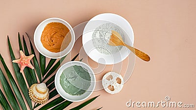 Homemade clay mask recipe concept. Top view cosmetic facial masks in bowls and tropical leaf on peach background. Face skin care, Stock Photo