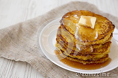 Homemade corn meal Johnny cakes on a white plate on a white wooden table, side view. Copy space Stock Photo