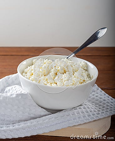 Homemade crumbly cottage cheese on a wooden background. Stock Photo