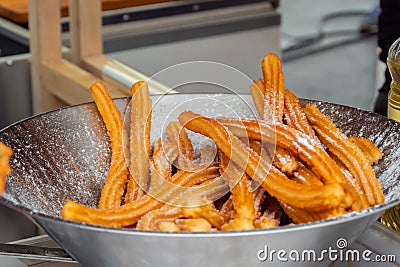 Homemade crunchy churros in steel bowl at summer outdoor food market Stock Photo