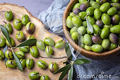 Homemade crushing olive making. Fresh green olives are breaking one by one. Crushing olives with stone. Preparing pickled olives Stock Photo