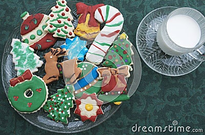 Homemade Decorated Cutout Christmas Cookies On Clear Plate,Green Tablecloth, Glass of Milk Stock Photo