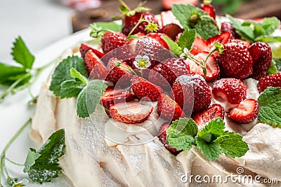 Homemade delicious meringue cake Pavlova with whipped cream, fresh strawberrie and mint. Food recipe background. Close up Stock Photo