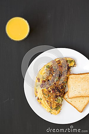 Homemade Denver Omelette on a white plate on a black surface, top view. Flat lay, overhead, from above Stock Photo