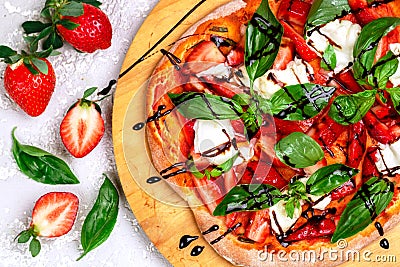 Homemade dessert pizza with tomato sauce, strawberries, burrata cheese, green Basil and balsamic Stock Photo