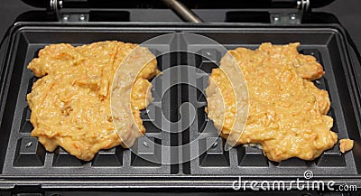 Homemade dough for carrot waffles on a waffle iron Stock Photo