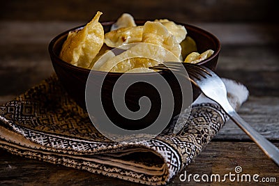 Homemade dumplings in clay pots on the kitchen table, fork and folklor napkin. Stock Photo