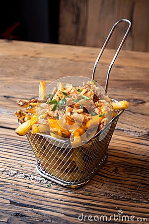 Homemade French fries with fried onions and melted cheddar a wooden table Stock Photo