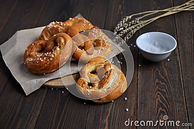 Homemade pretzels, salt and ears of wheat on a dark wooden table Stock Photo