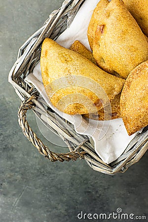 Homemade freshly baked Empanadas Turnover Pies with pisto vegetable cheese filling in tomato sauce in wicker basket. Stock Photo