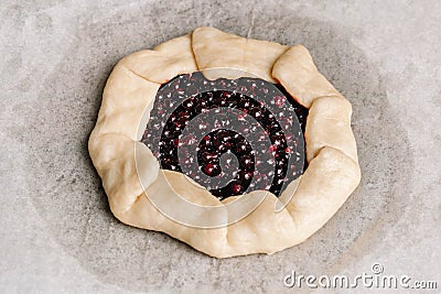 Homemade galette pie with red and black currants, blueberries and raspberries on wooden background Stock Photo