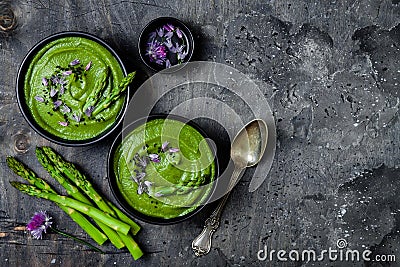 Homemade green spring asparagus cream soup decorated with black sesame seeds and edible chives flowers. Stock Photo