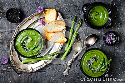 Homemade green spring asparagus cream soup decorated with black sesame seeds and edible chives flowers. Stock Photo