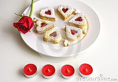 Homemade Heart shaped Almond Linzer cookies on white plate. Romantic set up red roses and candle lights ffor anniversary Stock Photo