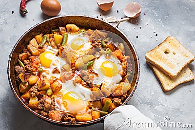 Homemade Hearty Breakfast Skillet with Eggs Potatoes and minced meat on concrete table Stock Photo